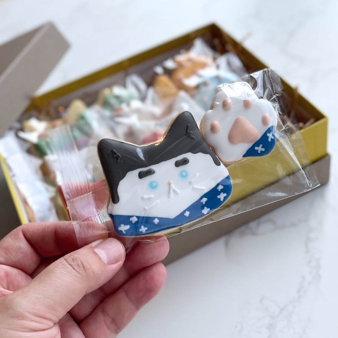 鹿児島ねこ（西郷さん）とにくきゅうクッキーを手に持った様子